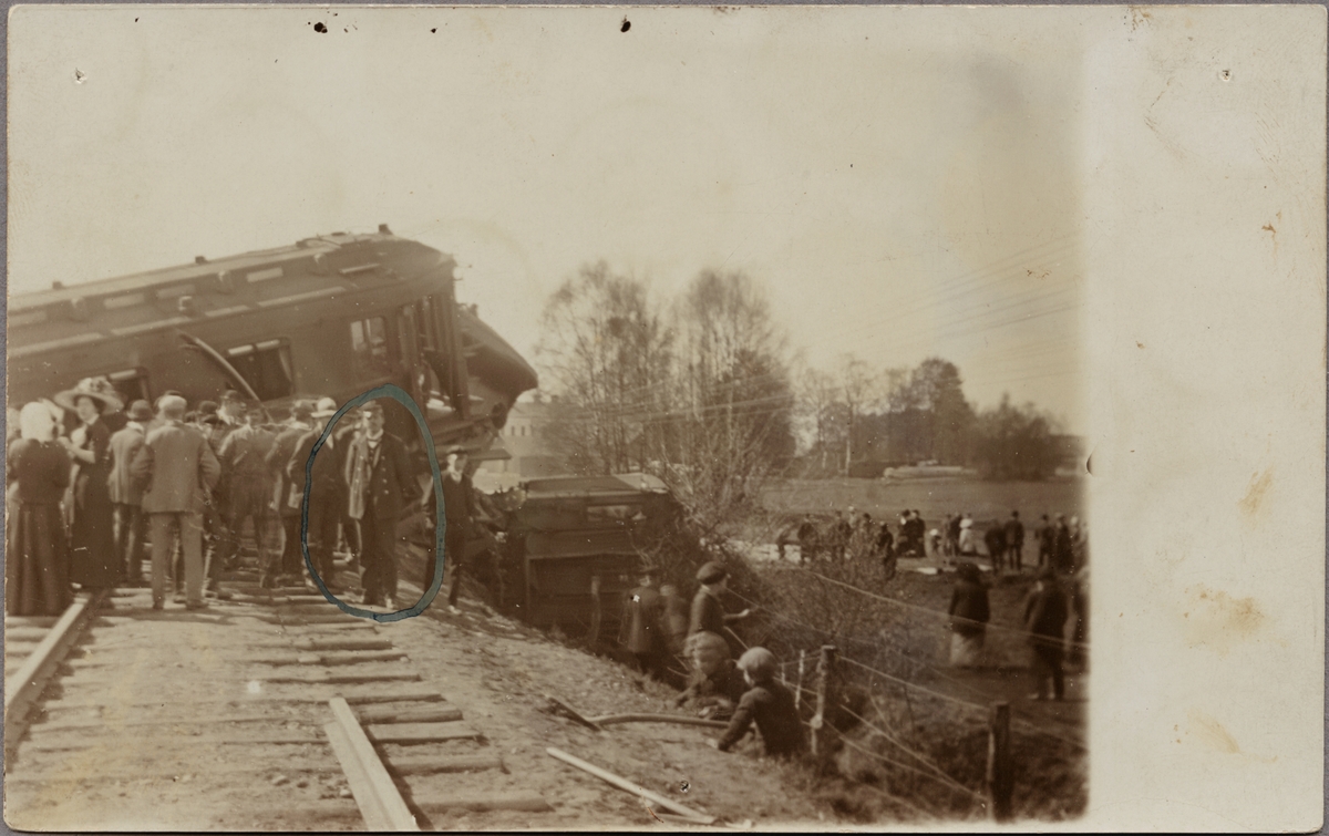 Åskådare har samlats för att se det tåg som spårat ur strax norr om Älmhult i riktning Vislanda. Mannen i uniform längst fram är konduktören Schütz från SOEJ, Sölvesborg-Ololfström - Älmhults Järnväg.