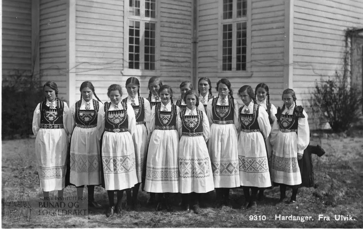 Konfirmantjenter framom Ulvik kyrkje i 1928. Alle er kledde i hardangerbunad. Utan hovudplagg, men håret er fletta.