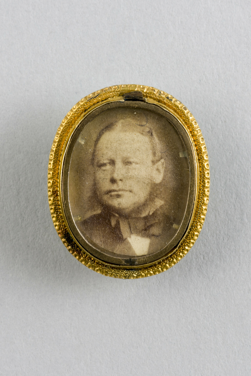 Del av pyntenål eller medaljong. Formet ovalt med fotoportrett av Jens Fabricius innrammet bak glass.