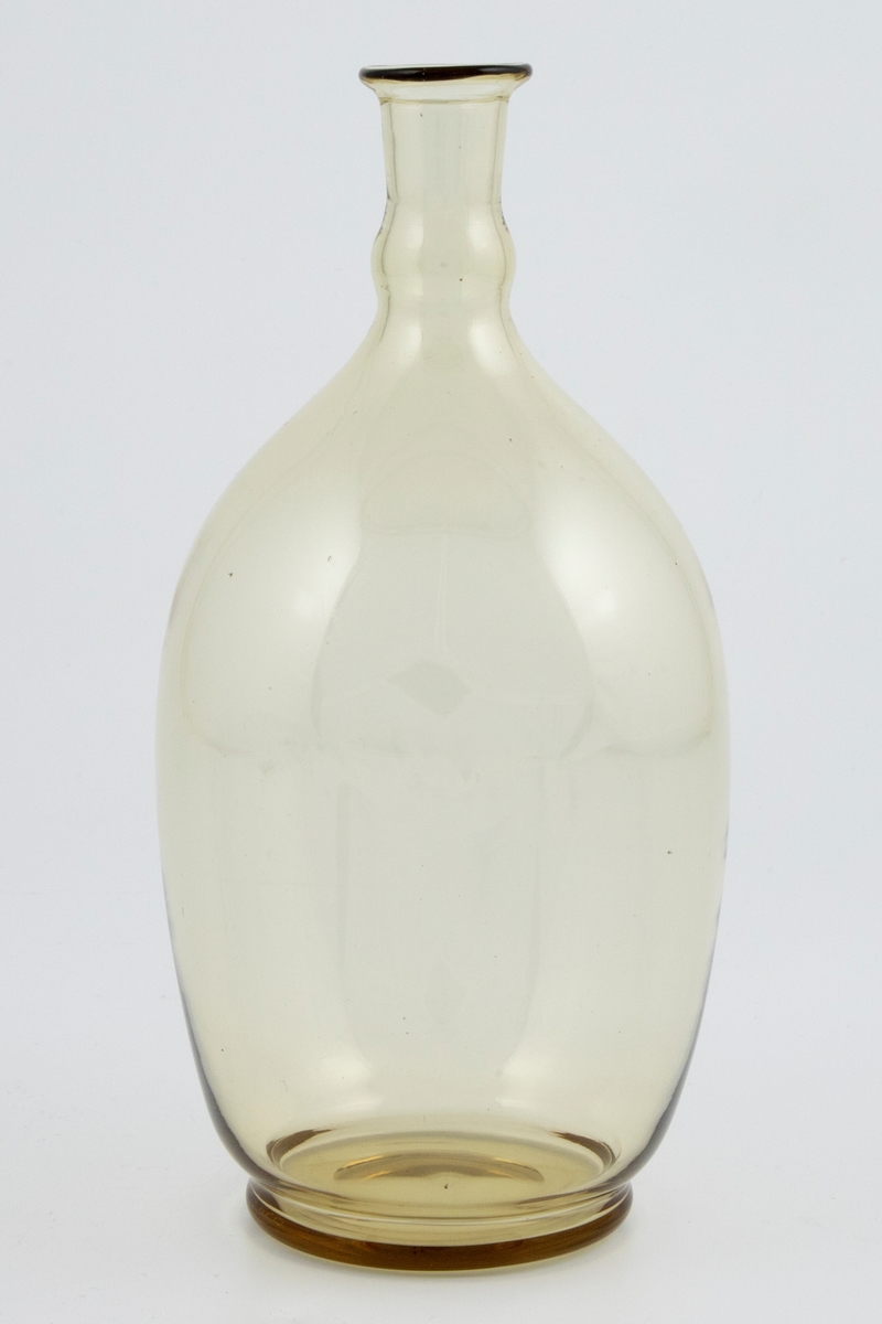 Vinkaraffelen er utført i olivengrønnfarget gjennomskinnelig glass. Korpus er ovalformet med lav hals.