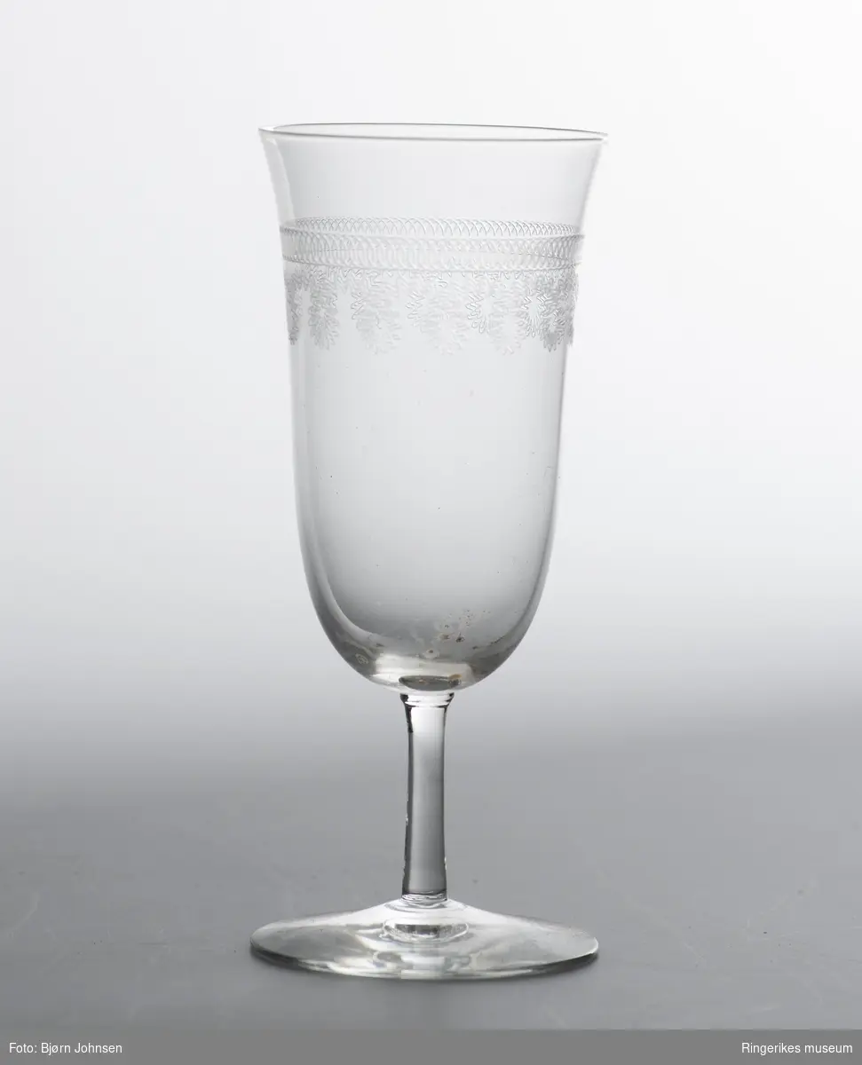 To hvitvinsglass dekorert med to forskjellige graverte mønsterborder øverst på glasset.