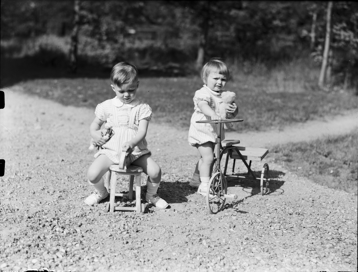 Två små barn leker ute med trehjuling och trähäst, Östhammar, Uppland 1953