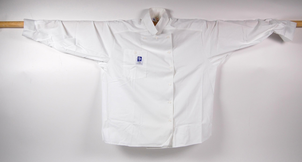 Hvit skjorte med påsydd merke med logo for de olympiske vinterleker på Lillehammer i 1994 på brystelommen.