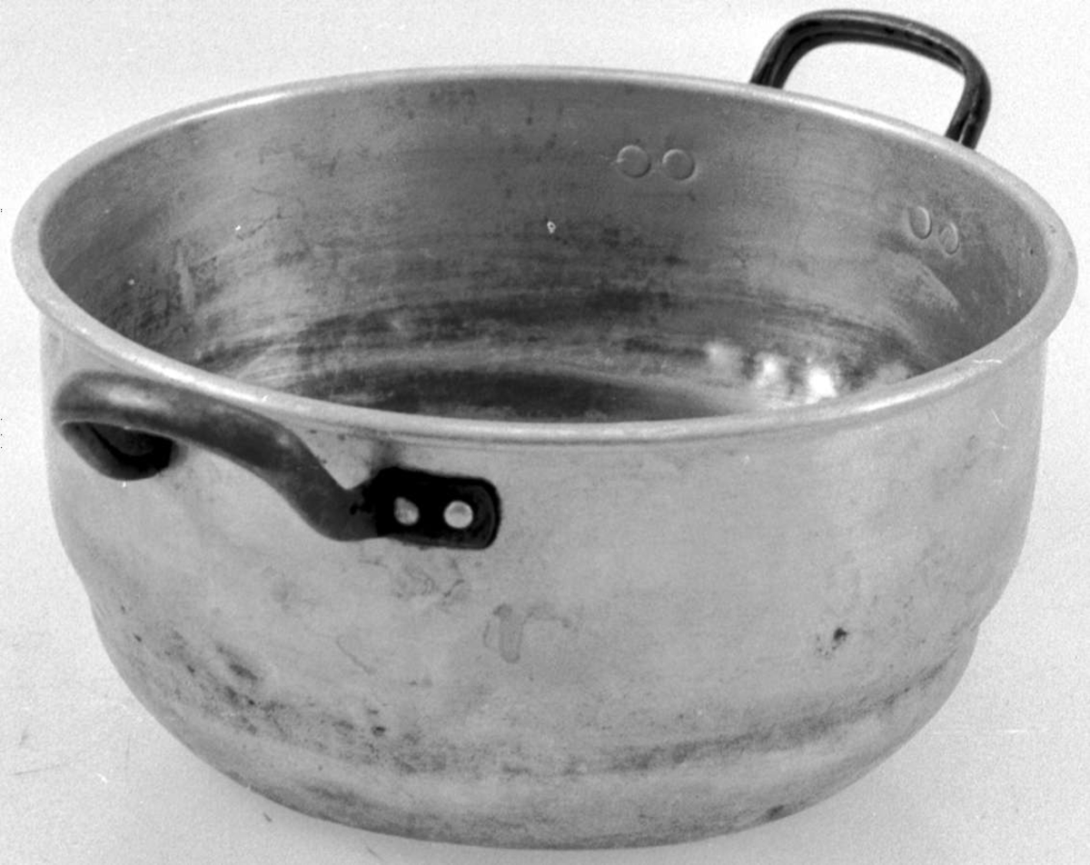 Kjele i aluminium med påklinkede hanker. Den har vært brukt på vedkomfyr.