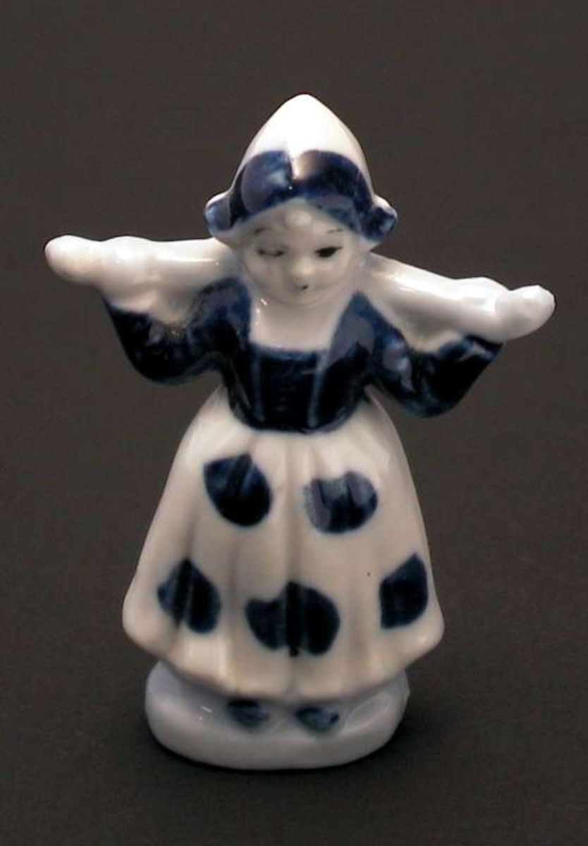 Porselensdame med hette og lang kjole som bærer et vassåk.