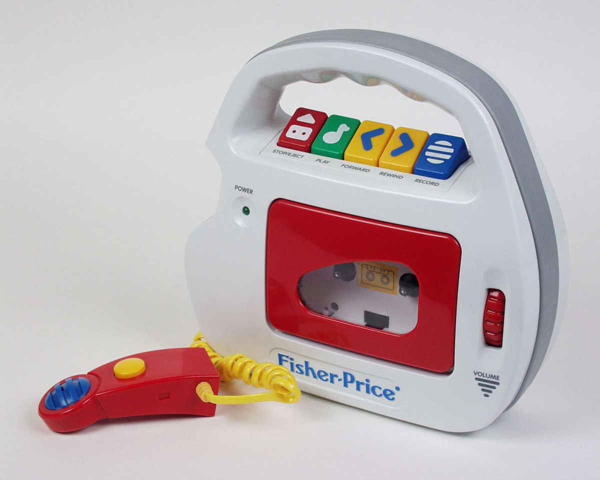 Kassettspiller for barn laget i grå plast med detaljer i farger og tydelige symboler. Den er batteridrevet og har håndtak. Mikrofonen har gul ledning og kan festes på siden.