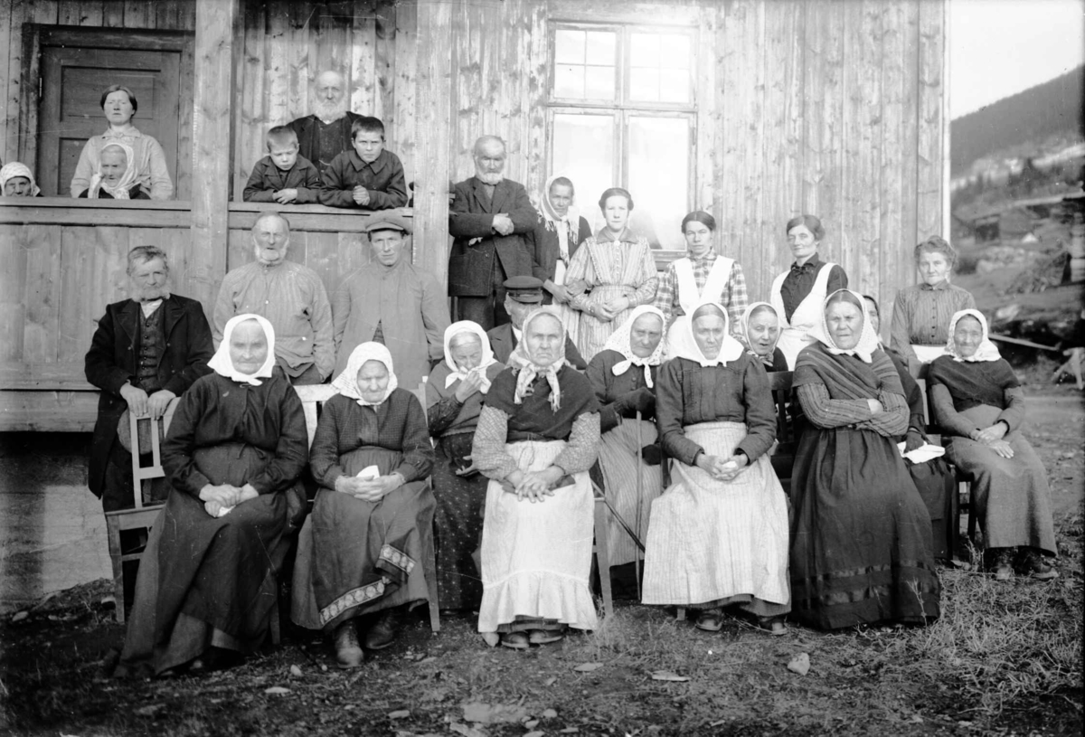 Gruppe med menn, kvinner og barn ved husvegg, gamlehjemmet Hemrom i Fåvang