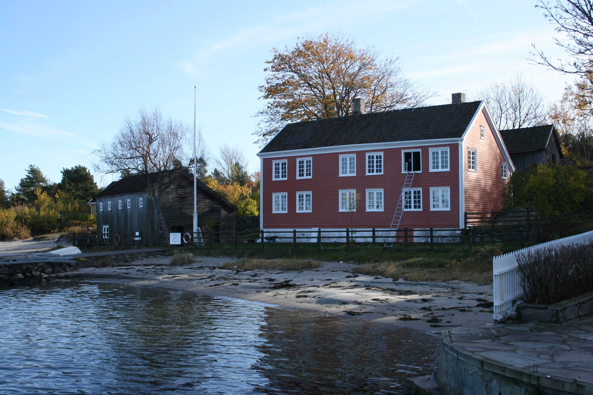 Merdøgaard, gårdstun sett fra V, sjøbod og våningshus t.v. og fjøs bak t.h.  Tunntreet, lønn, synlig over våningshuset. 

