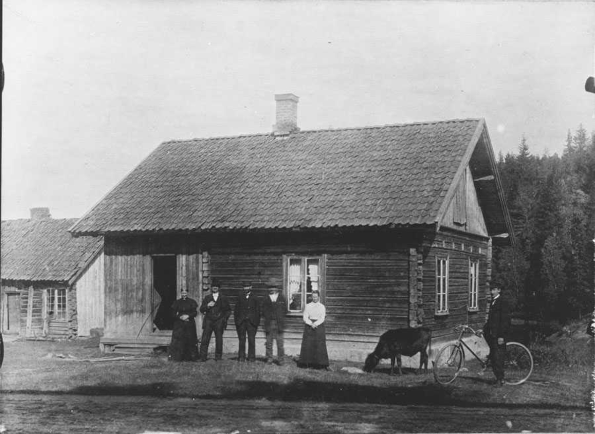 Grønslet. Huset til venstre er resten av den gamle hvilestua. 3 menn og 2 kvinner + en kalv og en mann på sykkel foran huset.