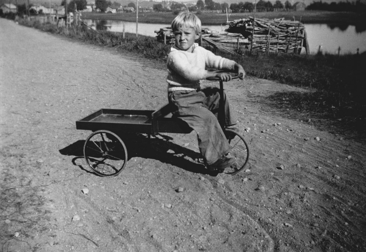 Liten gutt på trehjulssykkel med lasteplan.