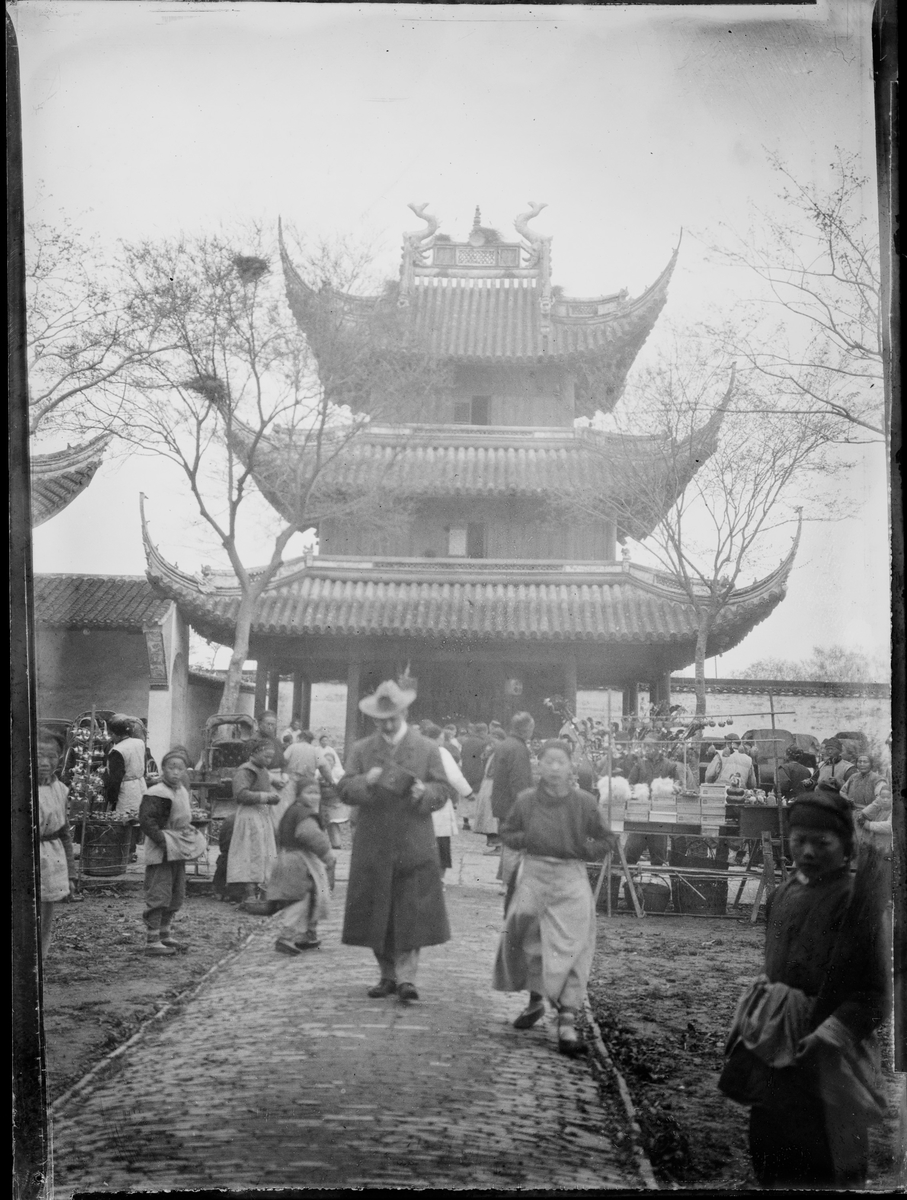 En turist blant flere mennesker av lokal befolkning foran et kinesisk tempel.