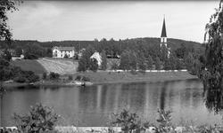 Kirke og gårdsbruk ved en elv.