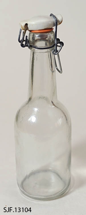 Flasken har en sylindrisk form og har en patentkork av metall og porselen. Mellom flaskeåpningen og korken er en rød strikk. Flasken har en flat bunn. 