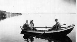4 menn i robåt på Mjøsa utenfor Kleven. Storbergsodden i bak