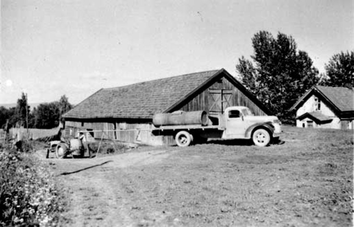 Eksteriør, uthus på Haug nedre , Nes, Hedmark. Åkersprøyte montert på en Ferguson Gråtass fylles fra vanntank på lastebil, en Chevrolet 1946-47 modell.