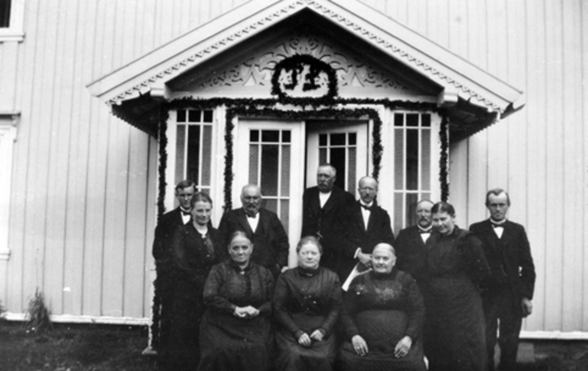 Begravelsen til Per Lier i juli 1918. Inngangsparti pyntet med granbar. Gruppe slektning på trappa. Bakerst er faren Thore Lier, moren Dina Lier står til høyre, ellers familie fra Brøttum og Ring.