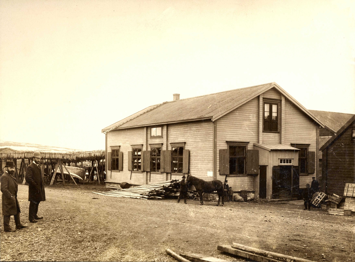 Esbensens butikk på Sletten i 1917. Hans Fredrik Esbensen med en annen mann i bildet. Fiskehjell i bakgrunnen.