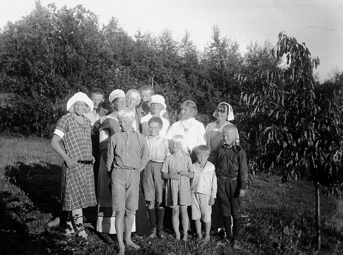 Gruppe, voksne og barn, hagen Kvalstua, Helgøya. 