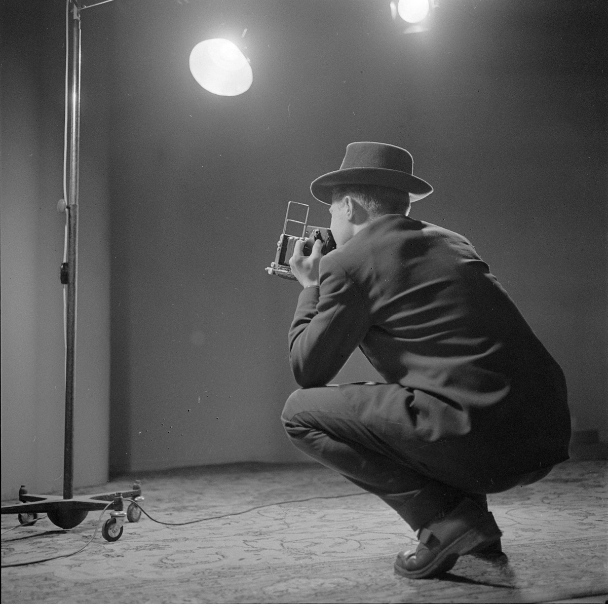 Fotograf med Speed Graphic pressekamera i fotostudio