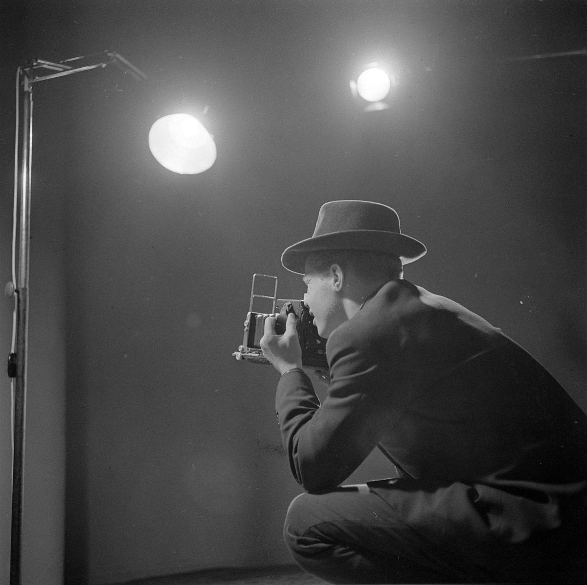 Fotograf med Speed Graphic pressekamera i fotostudio