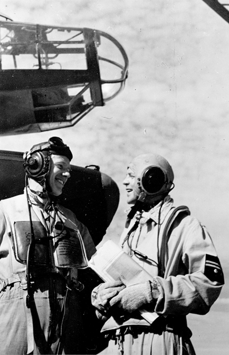 Två besättningsmän i flygutrustning samtal under nosen på flygplan T 2