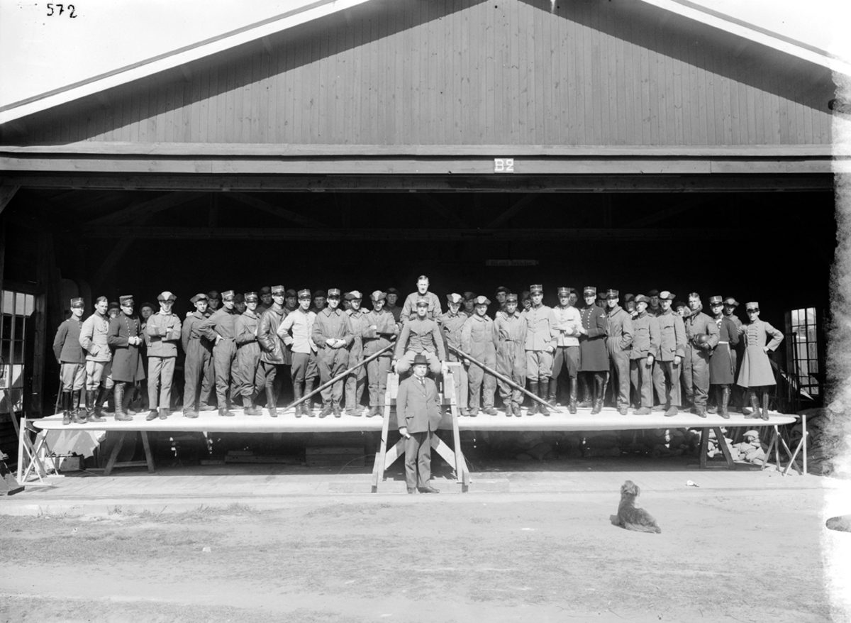 Grupporträtt. Provbelastning av flygplansvinge till flygplan J 23. Ett stort antal män står på en vinge i hangar.