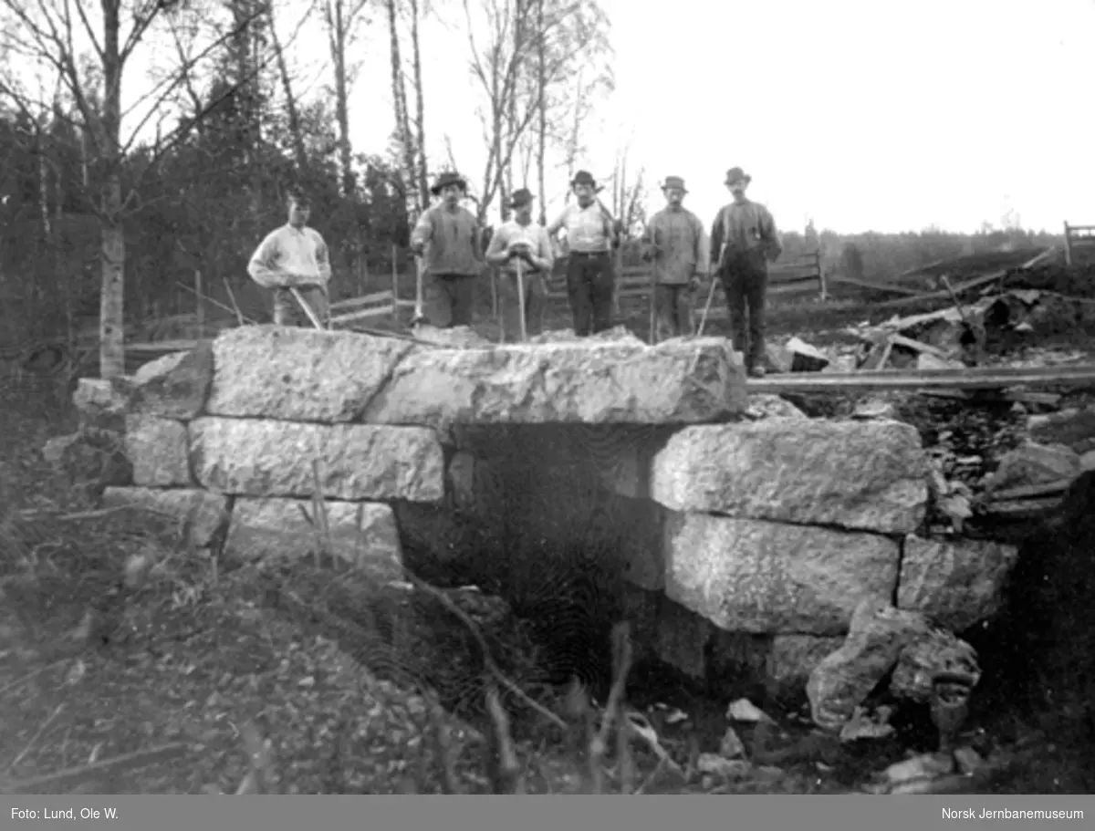 Fra anlegget av Holmestrand-Vittingfossbanen : seks anleggsarbeidere poserer på ei steinbru
