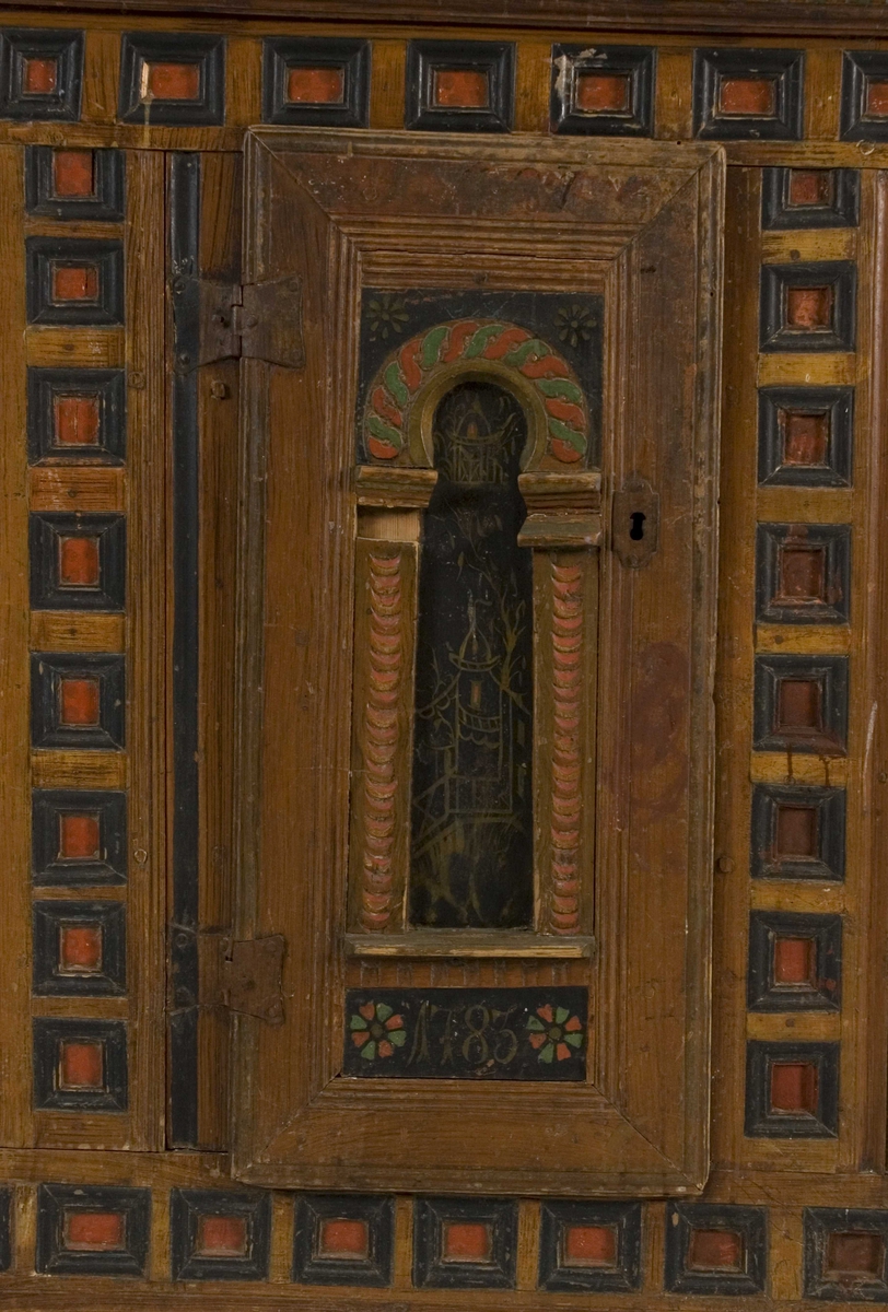 Skap i to deler. Høy skjenkebord, lav overdel. Skåret dekor i gesims med dragehoder i konsollene. Kassetter med rammefyllinger som dekor i frontpanelene. På dørene er det også malte motiv innen romanske buer. På høyre dør malte bygninger, på venstre dør er motivet uleselig. Ådret på sidene.