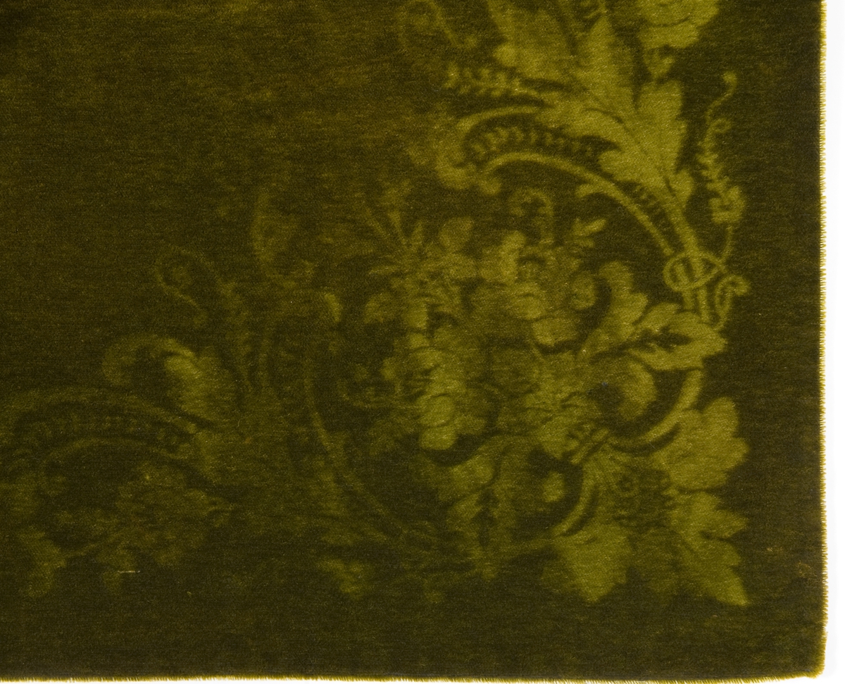 Grønt bordteppe av fløyel med presset mønster.