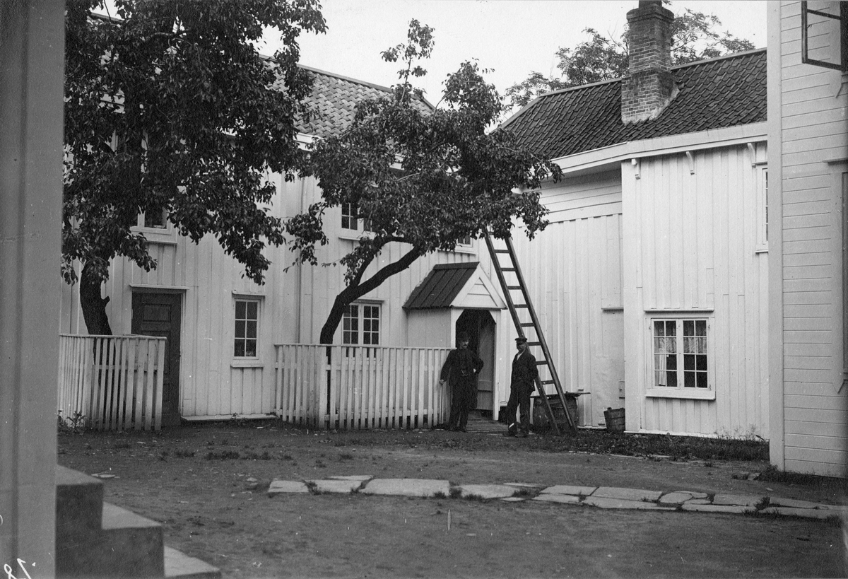 Baksiden av Christiegården i Kristiansund i Møre og Romsdal, fotografert i 1908. Menn står i bakgården med en stige.
Lunds nr.81.
