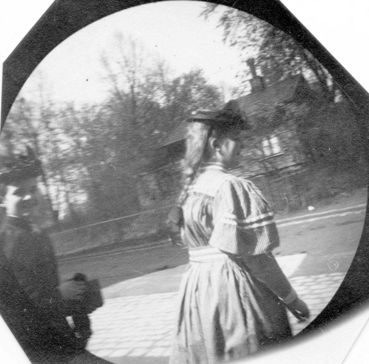 Frk. Bolla Nissen, til høyre, datter av general Nissen, og en annen kvinne, foran et mørkt hus i hage.