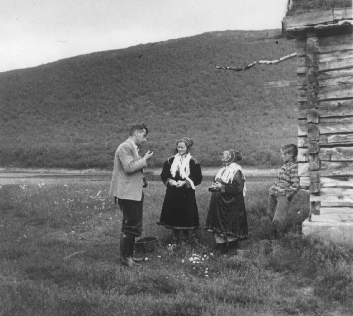 Dr. A. Nesheim i samtale med Ellen R. Vuolab og Ravna V. Nikkinen  ved et hushjørne. Javrebainjarga 1952.