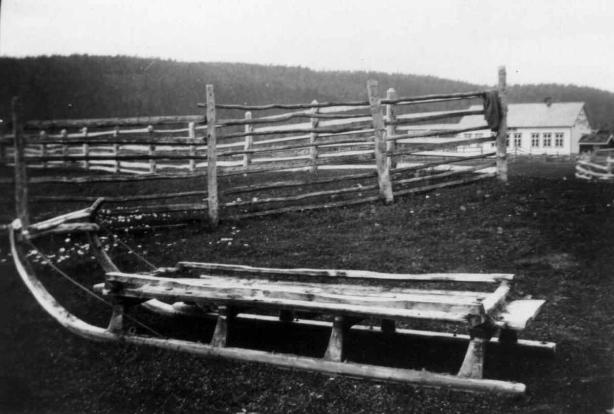 Slede av finsk type foran et gjerde. I bakgrunnen en bolig. Karasjok 1933.
