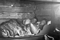 To menn ligger i en seng på en hytte ved Burresjøen, Guldale