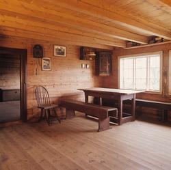 Gammel stue med bord, benk veggur og stol. Illustrasjonsbild