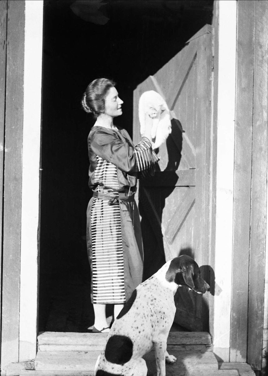 Juni 1925. Guri Arentz fotografert i døråpningen med katten.  Hunden Wapi sitter i forgrunnen.