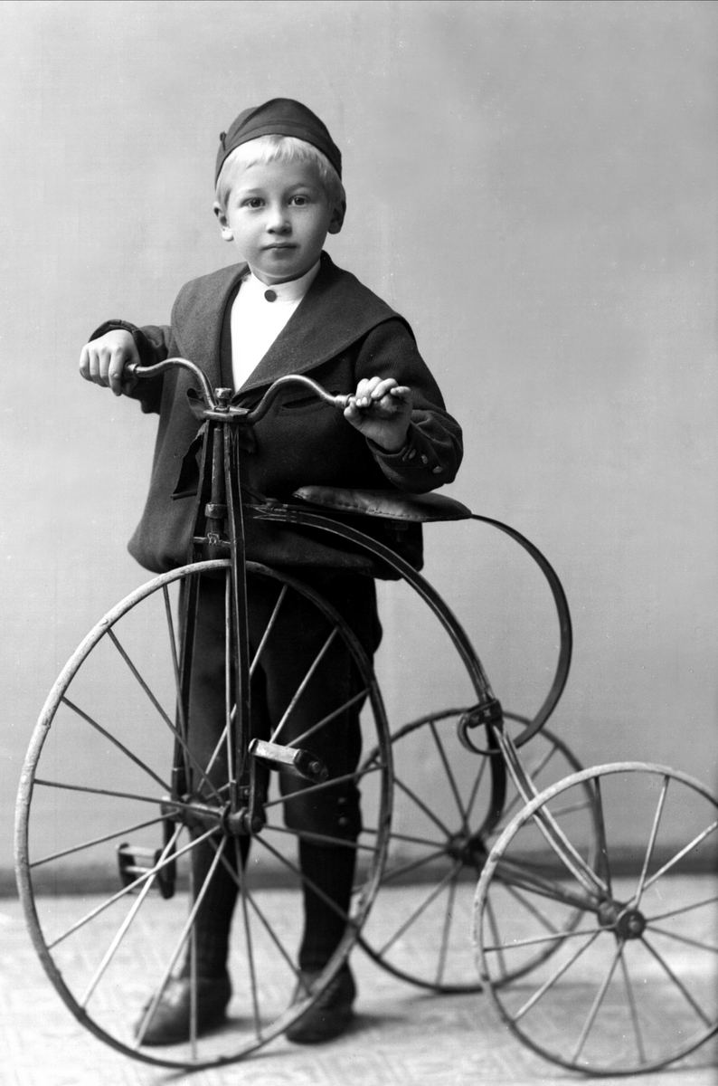 Portrett, gutt på en trehjulsykkel, ca 1892. Kristen Thrue.