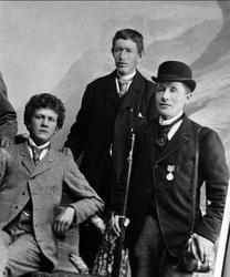 Avfotografering. Gruppeportrett, tre yngre menn, en med gevæ