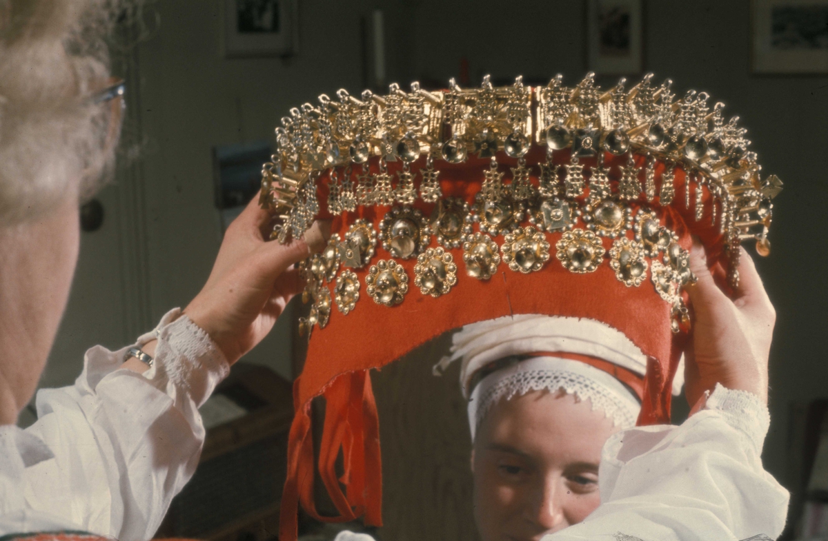 Brudepynting, Jølster 1967.Bruden, Eva Eide, får hjelp av Maria Gjesdal  med påkledningen.
Sølvet, også kalt "huldersølvet",  settes på 