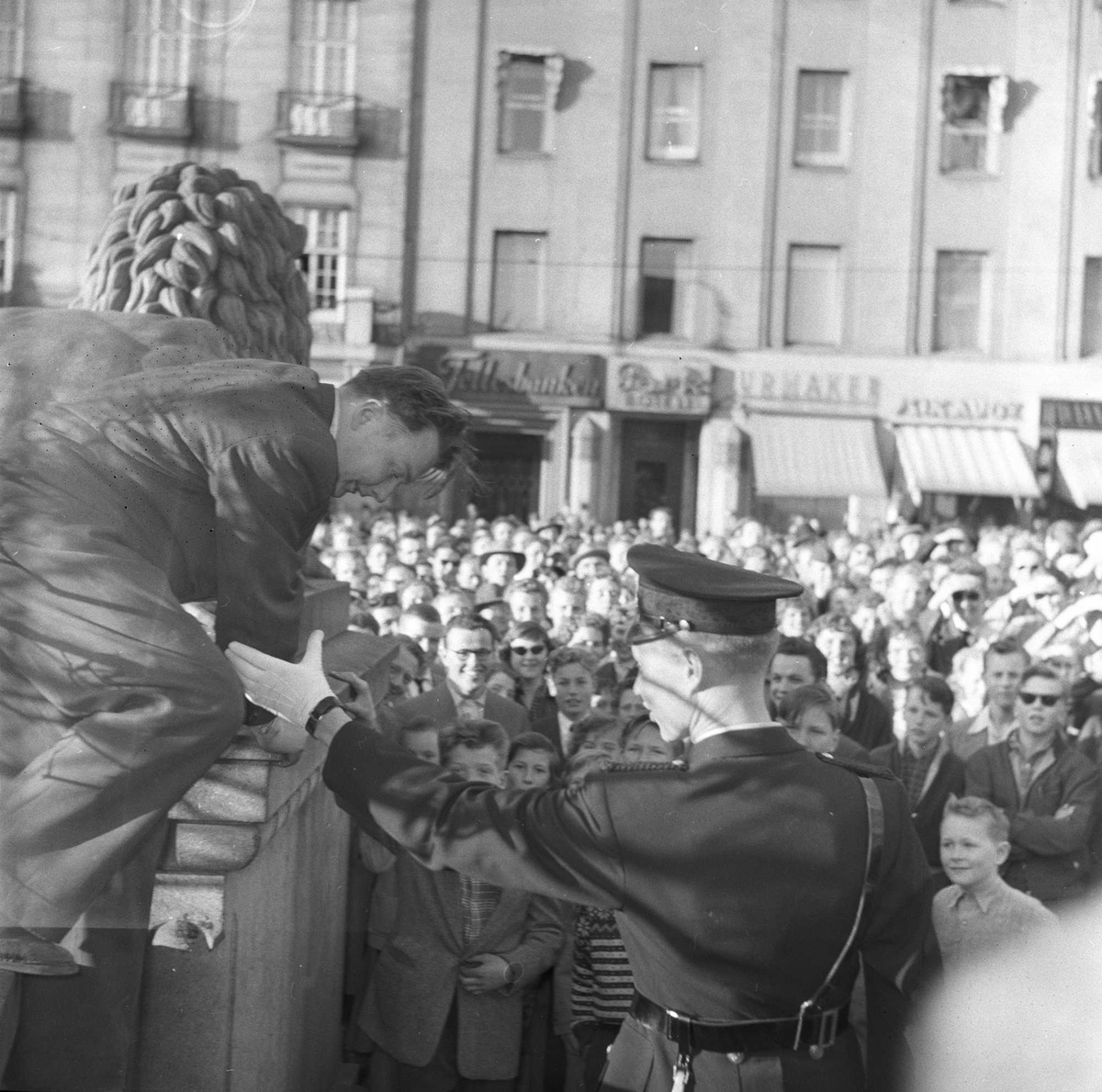 1. mai feiring, Oslo 1956. Politimann drar person ned fra statue. Folkemengde i bakgrunnen.