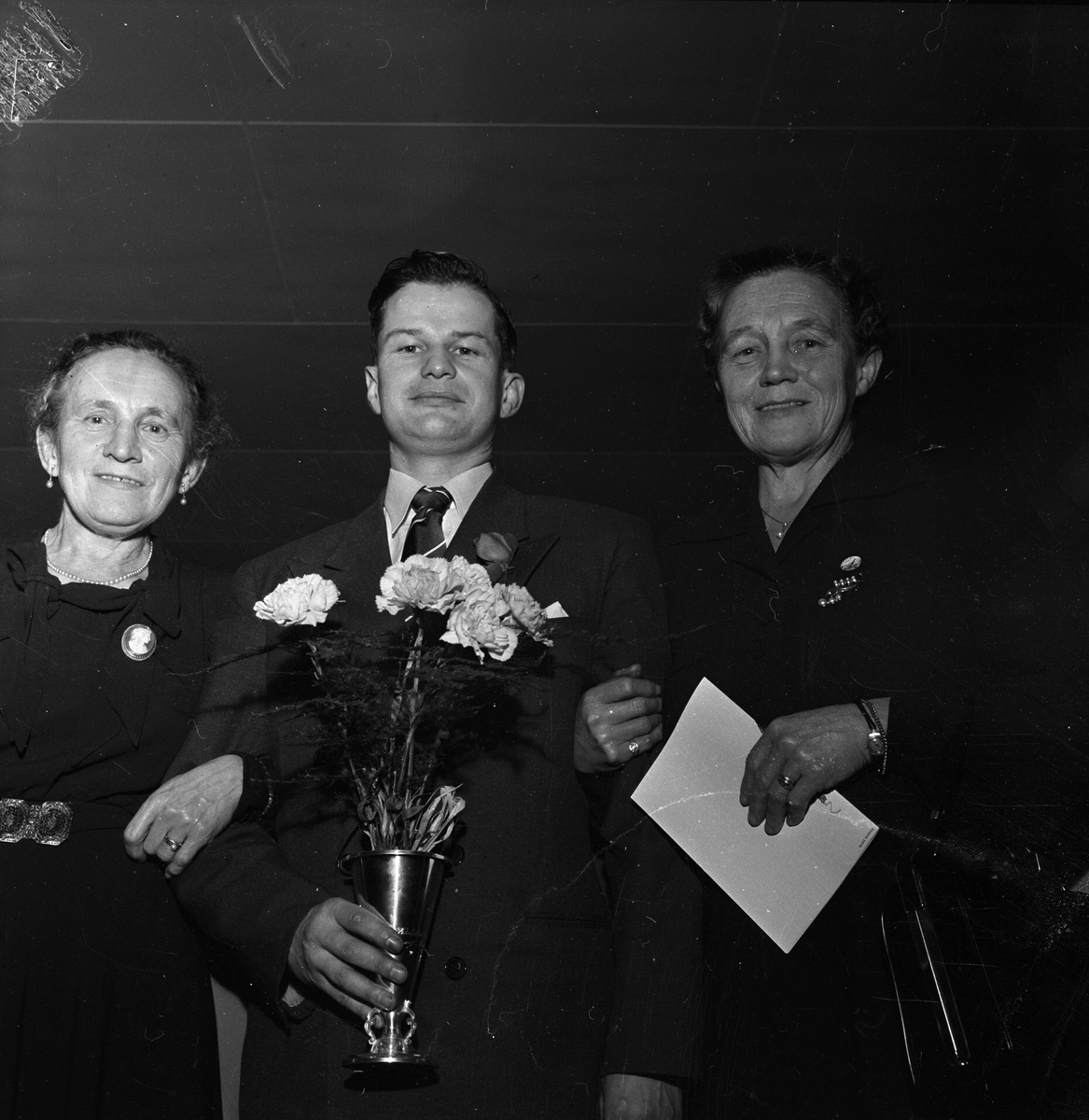 Kvinne og to menn med blomster og pokal 30.11.1953. Bygdelag, Norefjellaget.