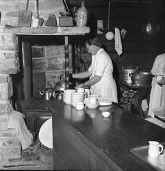 Finnskogen, august 1956. Marken. Interiør, kjøkken, kvinne m
