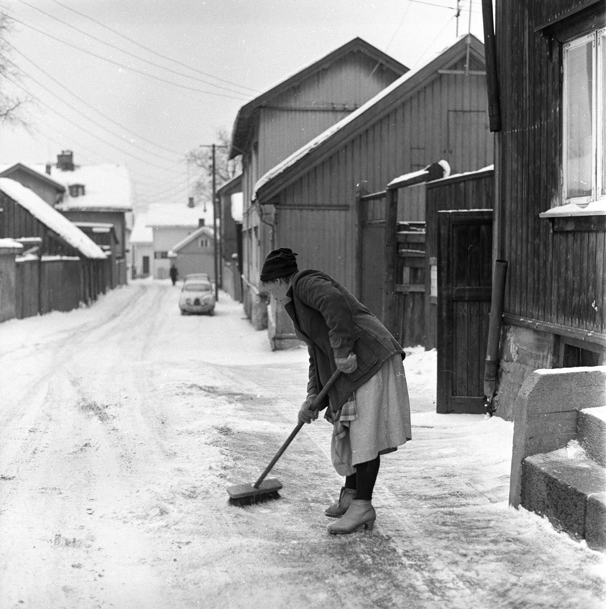 Tromsøgata, Rodeløkka, Oslo, januar 1963. Trehusbebyggelse og kvinne som soper.