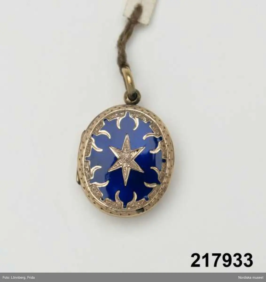 Katalogkort:
"Medaljong, guld med blå emalj,
H. 2,7 cm

Innehåller hårlock."