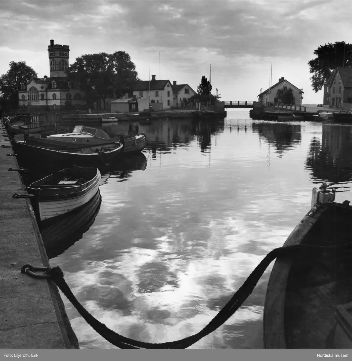 Piren i Fiskarehamnen i V&auml;stervik med plats f&ouml;r fritidsb&aring;tar. Mitt i bild ses Lilla Str&ouml;mmen. Till v&auml; Str&ouml;msholmen med gamla Varmbadhuset, byggt 1910, st&auml;ngt 1975.