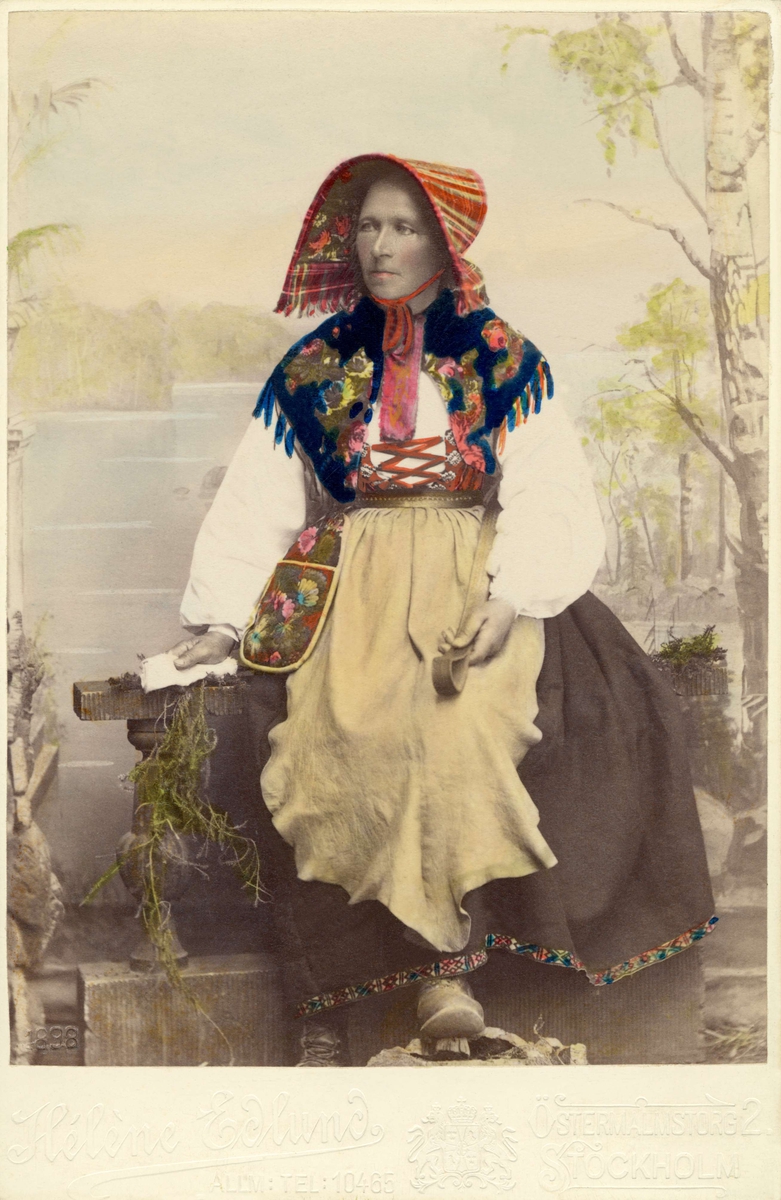 "Från utställningen 1897." En kvinna sitter klädd i dräkt från Dala-Floda, Dalarna.