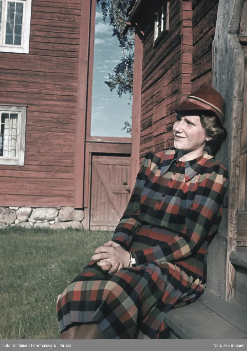 Kvinna i rutig klänning och röd hatt.
