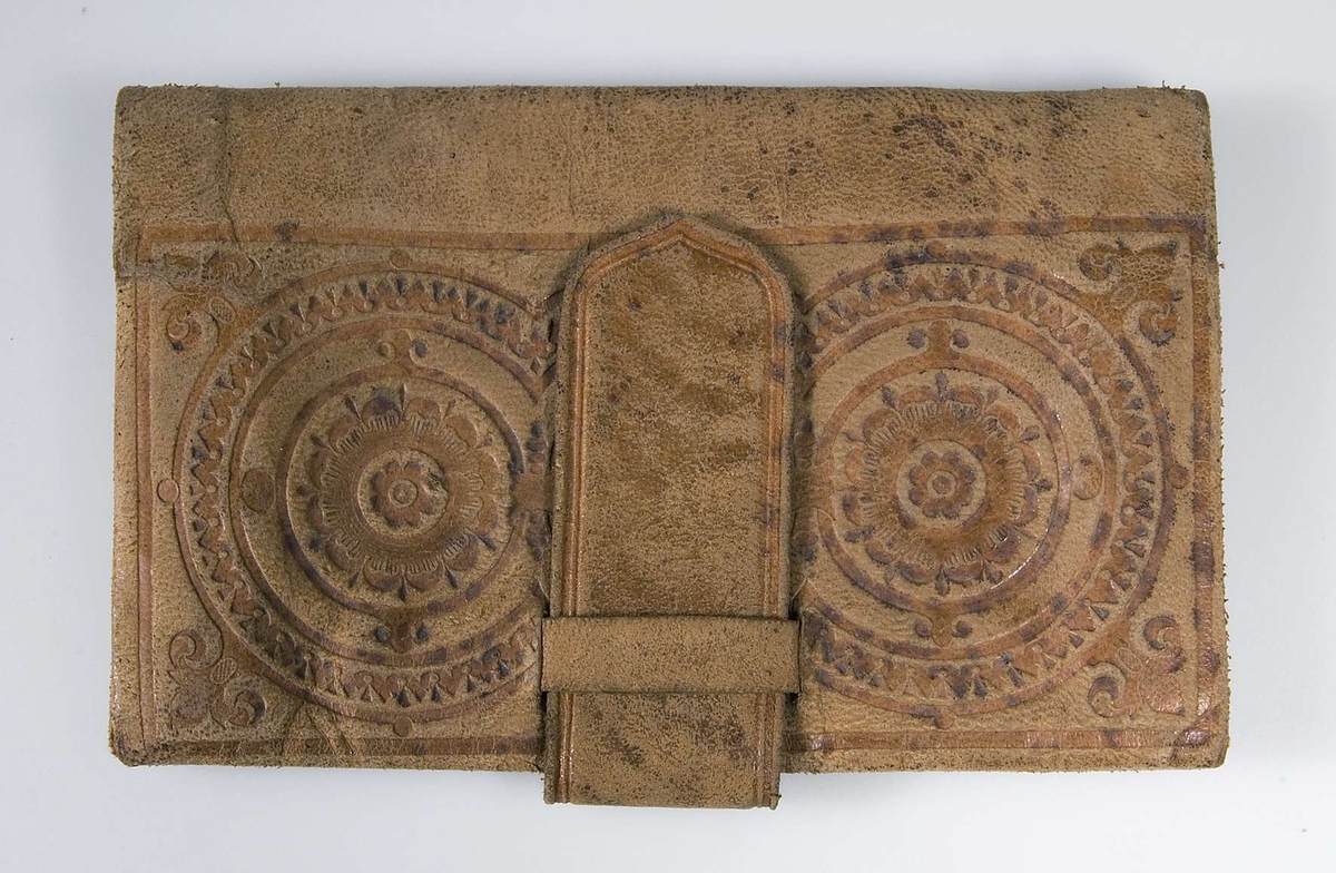 Plånbok av brunt läder med pressad dekor. Två fack.
 
