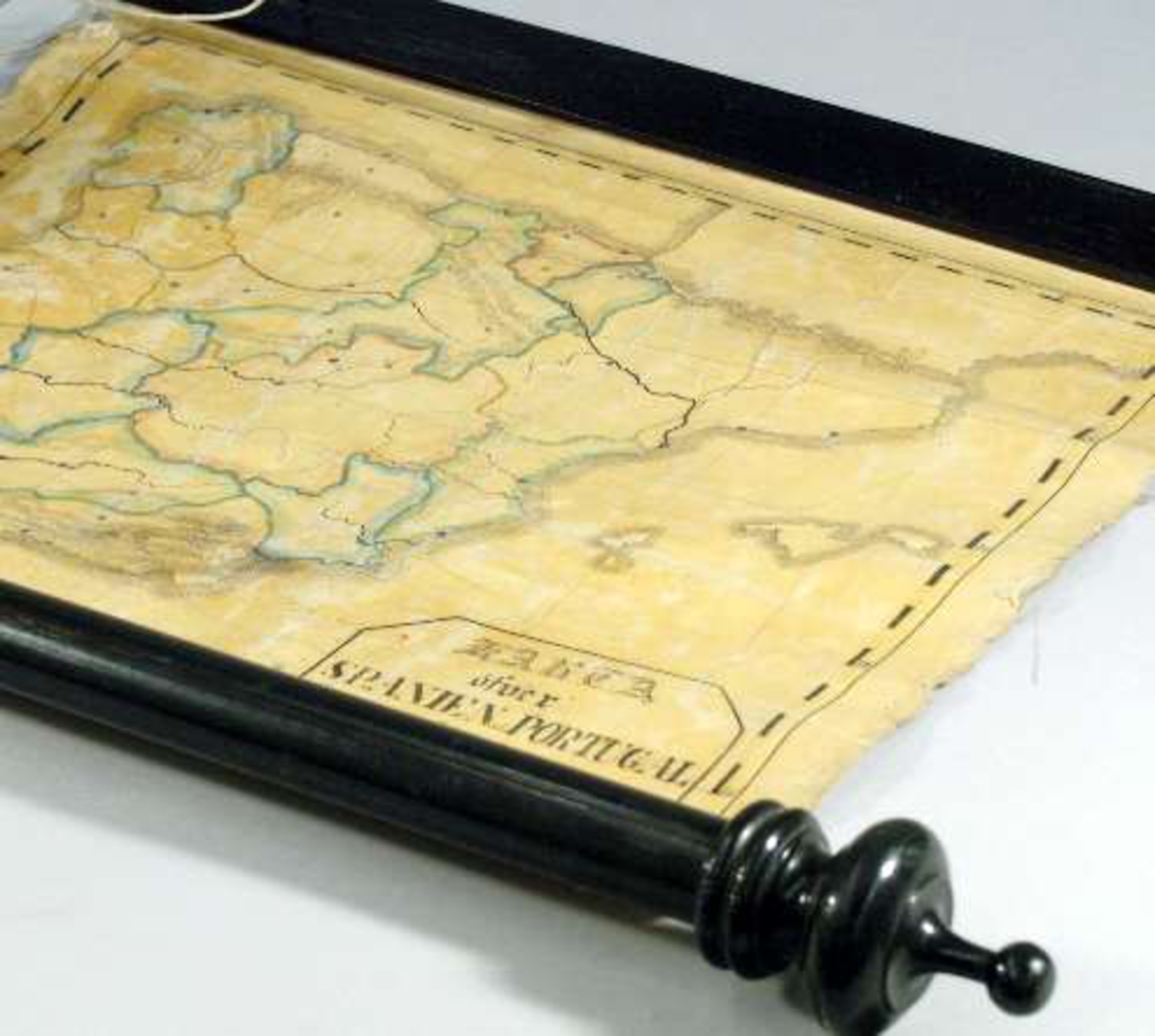 Blindkarta över Spanien och Portugal på vävd duk rullad runt en trästång. Text på kartan: KARTA öfver Spanien och Portugal, Ritad af P. A. Malmberg.