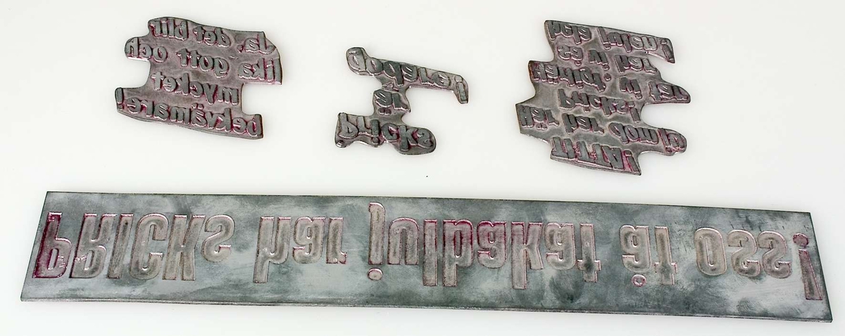Fem klichéer av metall, olika storlekar. Alla klichéerna har förvarats i samma paket, med omslagspapper från Hugo Löjdquist Tryckeri, Tierp.
